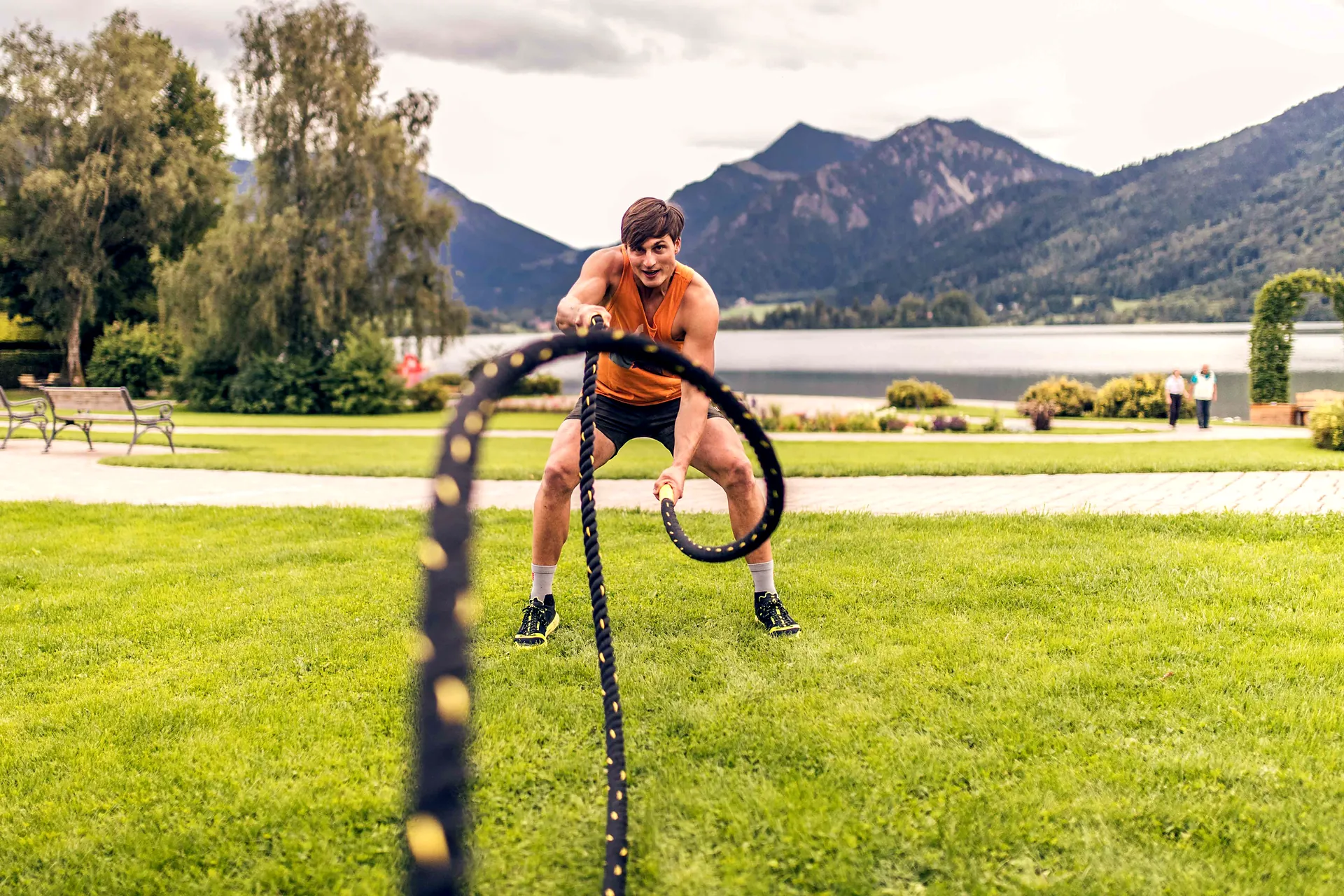 Training mit Battle Ropes im Park am Schliersee, dahinter See und Berge